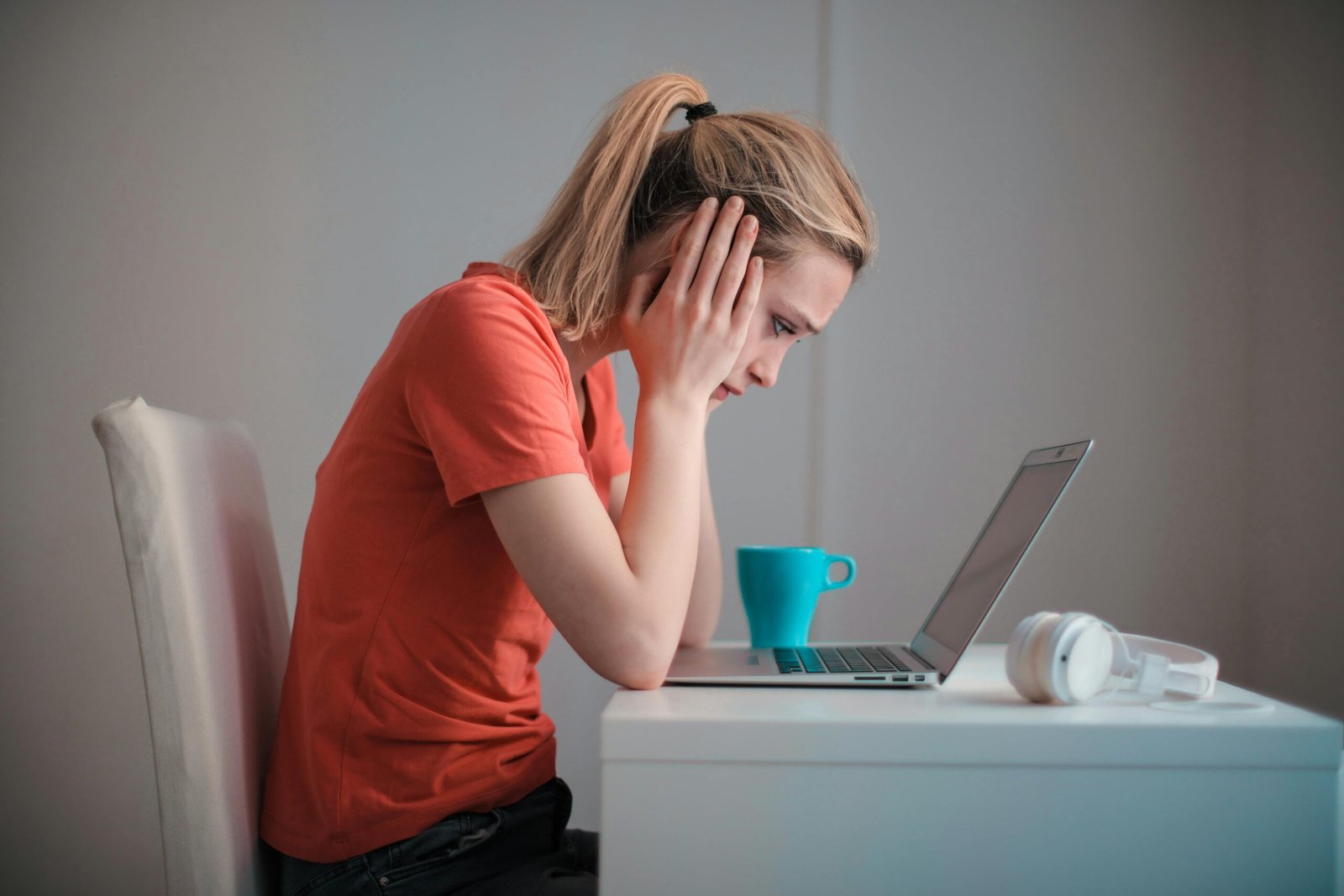 Mujer sentada en escritorio viendo su computadora con cara angustiada o preocupada