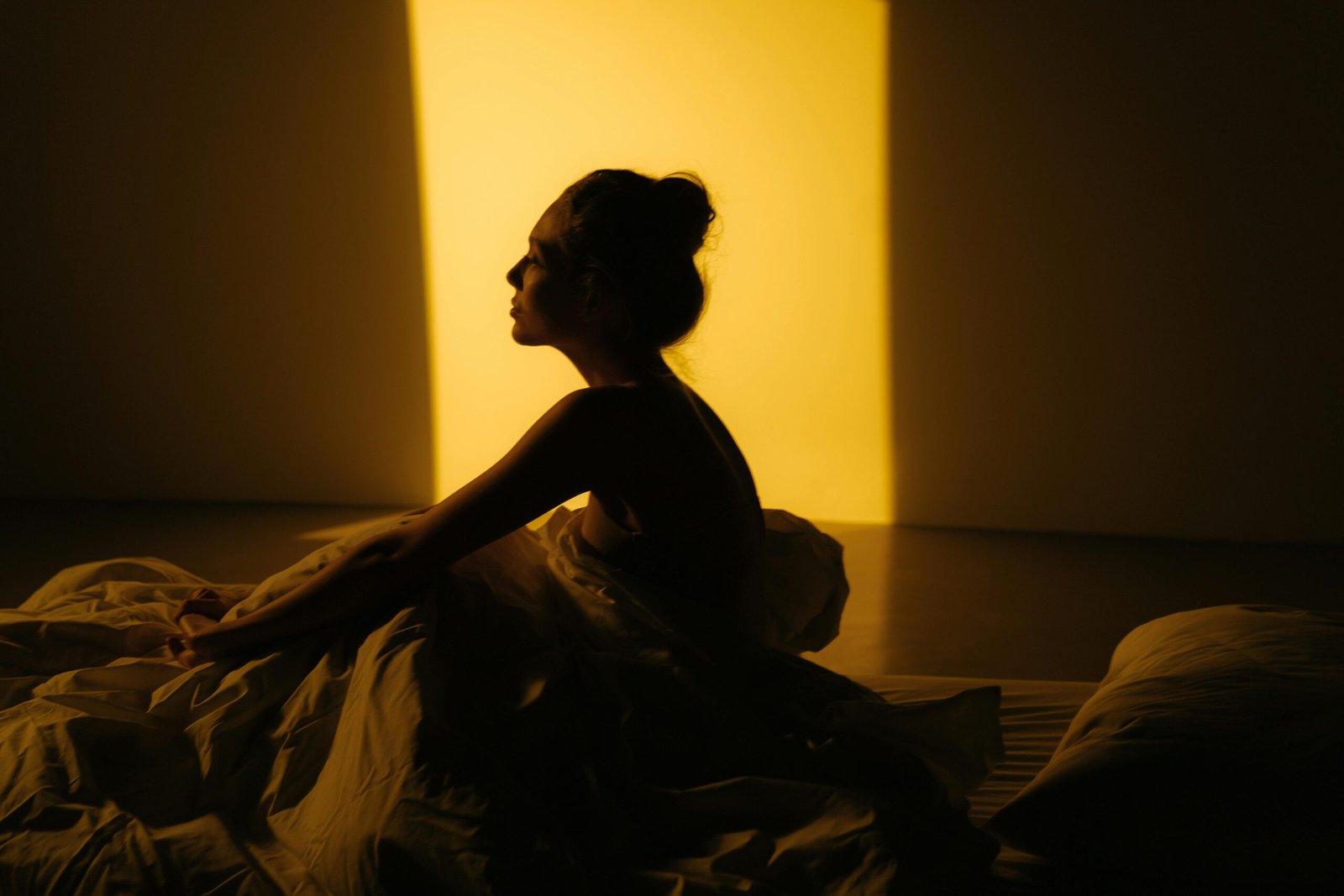 Mujer preparándose para dormir anocheciendo, sentada en su cama
